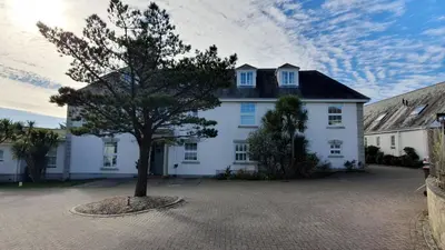 a white house with a tree in front of it at 3 The Manor - Opposite a golf course - Pet friendly - Wi-Fi in Uny Lelant
