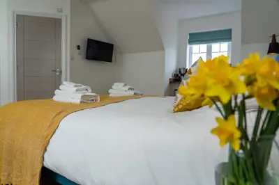 a bedroom with a bed with yellow flowers in a vase at The Coffee Loft in Padstow
