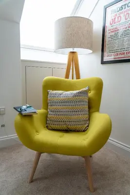 a yellow chair with a pillow and a lamp at The Coffee Loft in Padstow