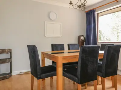 a dining room with a wooden table and black chairs at Three Jays in Looe