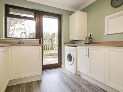 a kitchen with white cabinets and a washing machine at Three Jays in Looe