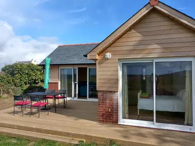 a house with a deck with a table and chairs at Orchard Chalet in Liskeard