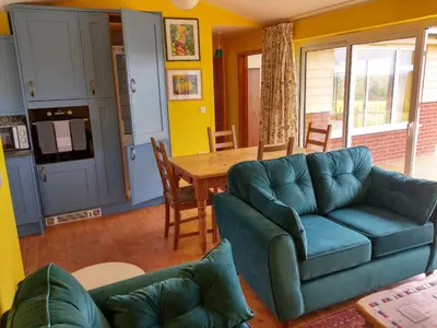 a living room with a couch and a table at Orchard Chalet in Liskeard