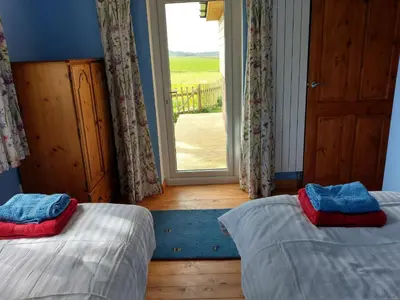 a room with two beds and a window with a door at Orchard Chalet in Liskeard