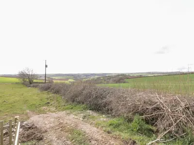 a dirt road in a field next to a fence at Orchard Chalet in Liskeard