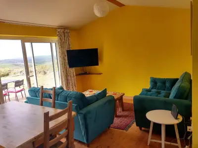 a living room with a couch and a table and a tv at Orchard Chalet in Liskeard