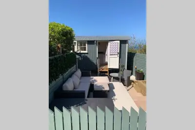 a backyard with a fence and a house at Trevone Luxury Shepherds hut close to the beach in St Merryn