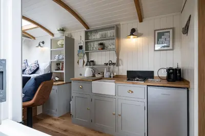 a kitchen with white cabinets and a sink at Trevone Luxury Shepherds hut close to the beach in St Merryn
