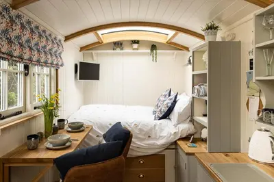 a room with a bed and a table and chairs at Trevone Luxury Shepherds hut close to the beach in St Merryn