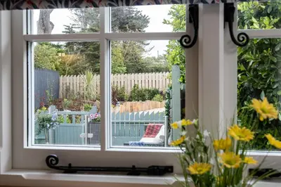 a window with a view of a garden with flowers at Trevone Luxury Shepherds hut close to the beach in St Merryn