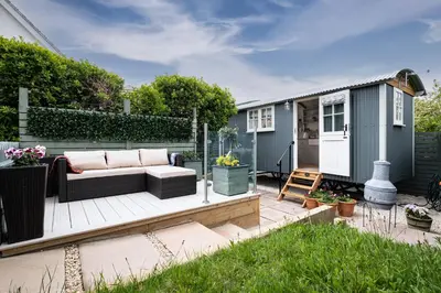 a backyard deck with a couch and a tiny house at Trevone Luxury Shepherds hut close to the beach in St Merryn
