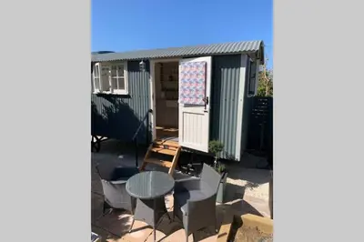 an image of a caravan with a table and chairs at Trevone Luxury Shepherds hut close to the beach in St Merryn