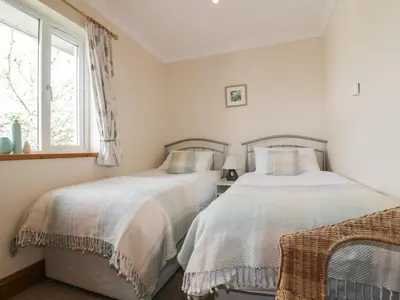 two beds in a bedroom with a window at Hazel Cottage in Tintagel