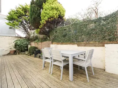 a white table and chairs on a wooden deck at Hazel Cottage in Tintagel