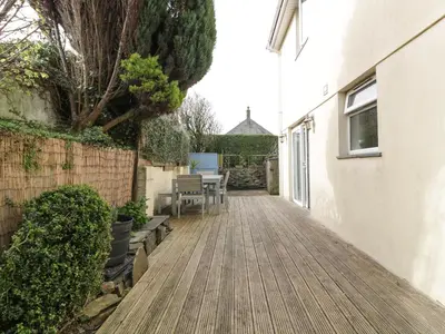 a patio with a table and benches on a building at Hazel Cottage in Tintagel