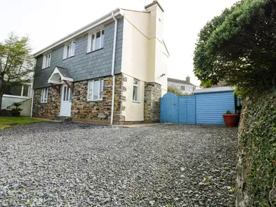 a house with a blue gate and a gravel driveway at Hazel Cottage in Tintagel