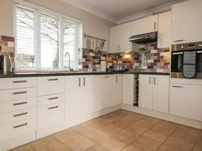 a kitchen with white cabinets and a microwave at Hazel Cottage in Tintagel