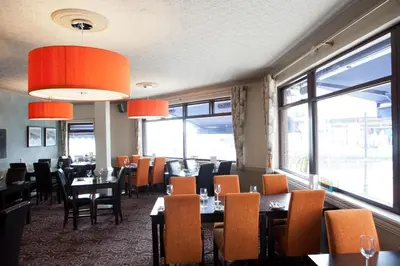 a dining room with tables and chairs and windows at Griffin Inn in Newquay
