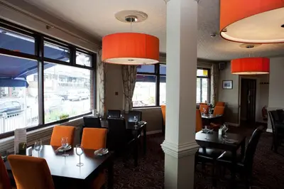 a restaurant with tables and chairs and windows at Griffin Inn in Newquay