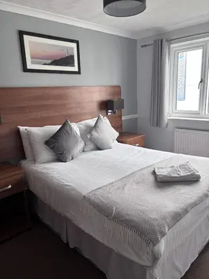 a bedroom with a large bed with white sheets and pillows at Griffin Inn in Newquay