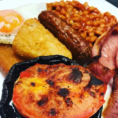 a plate of food with eggs sausage beans and bacon at Griffin Inn in Newquay