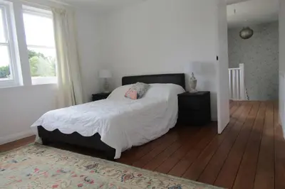 a bedroom with a large bed and a wooden floor at Lovely 3 Bed House Close to Carlyon Bay Beach! in Carlyon Bay