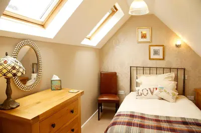 a bedroom with a bed with a dresser and a mirror at The Dog House, Penryn in Penryn