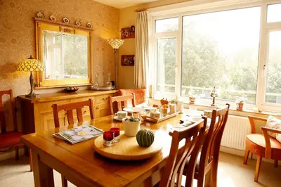 a dining room with a wooden table and a large window at The Dog House, Penryn in Penryn