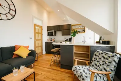 a living room with a couch and a kitchen at Manderley Penthouse in St Ives