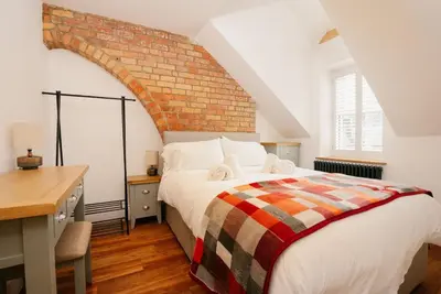 a bedroom with a large bed and a brick wall at Manderley Penthouse in St Ives