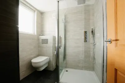 a bathroom with a toilet and a glass shower at Manderley Penthouse in St Ives