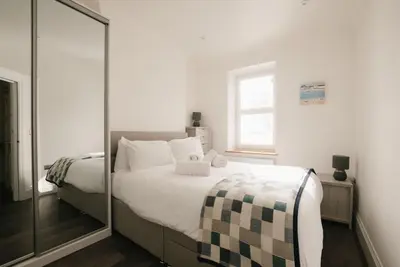a bedroom with a large bed and a mirror at Harbour Vista in St Ives