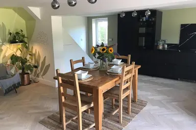 a wooden table with chairs and a vase of flowers on it at Little Chi in Truro