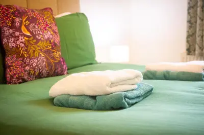 two towels are sitting on a green bed at Polrunny Farm Elderberry Cottage with sea view in Boscastle