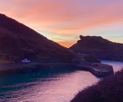 a sunset over a body of water with a mountain at Polrunny Farm Elderberry Cottage with sea view in Boscastle
