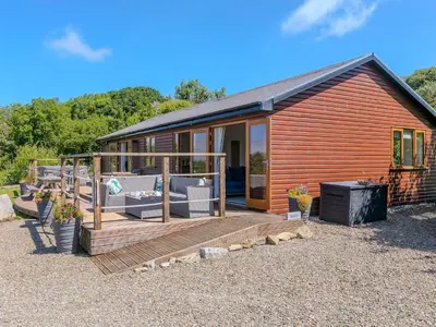 a wooden cabin with a large deck with furniture at Mellydonen Beder Del Melly, Tor Down Quarry in Bodmin