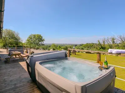 a jacuzzi tub on a deck with a table at Mellydonen Beder Del Melly, Tor Down Quarry in Bodmin