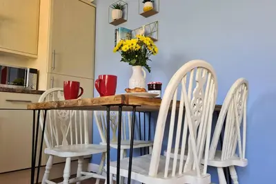 a dining room table with two chairs and a vase with flowers at Driftwood Cottage in Uny Lelant