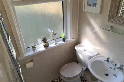 a bathroom with a toilet and a sink and a window at Driftwood Cottage in Uny Lelant