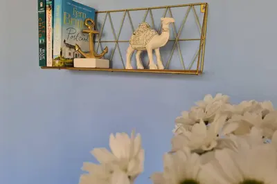 a shelf with a book and a toy camel and flowers at Driftwood Cottage in Uny Lelant