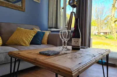 a wooden table with a bottle of wine and a wine glass at Driftwood Cottage in Uny Lelant