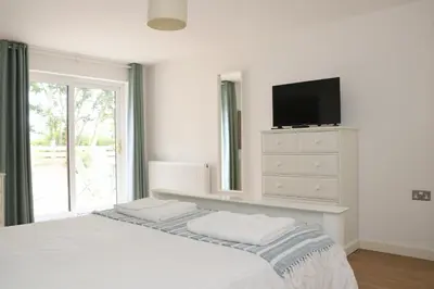 a bedroom with a bed with a tv on a dresser at Otters Holt in St Merryn