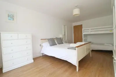 a bedroom with a white bed and a desk at Otters Holt in St Merryn