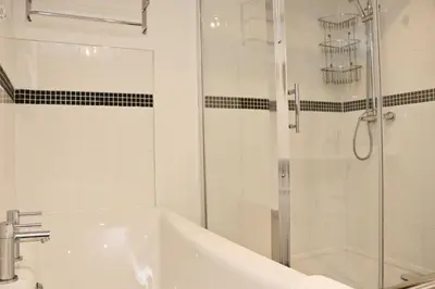 a bathroom with a shower and a tub and a sink at Otters Holt in St Merryn