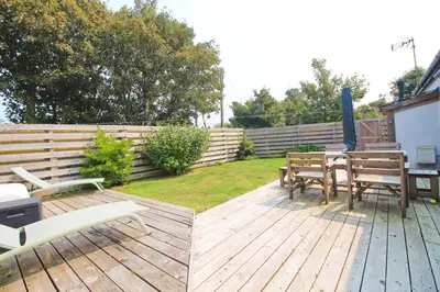 a wooden deck with a table and chairs on it at Otters Holt in St Merryn