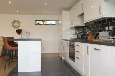 a kitchen with white cabinets and a counter top at Otters Holt in St Merryn