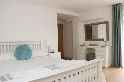 a white bedroom with a white bed and a mirror at Otters Holt in St Merryn