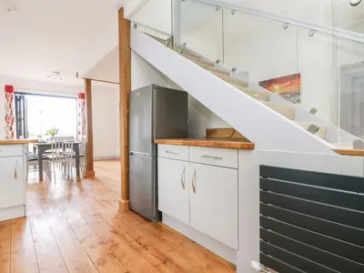 a kitchen with white cabinets and a staircase at Dovefields in Helston
