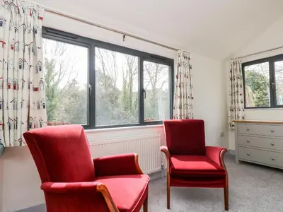 two red chairs in a room with a window at Dovefields in Helston