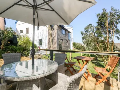 a patio with a table and chairs and an umbrella at Dovefields in Helston